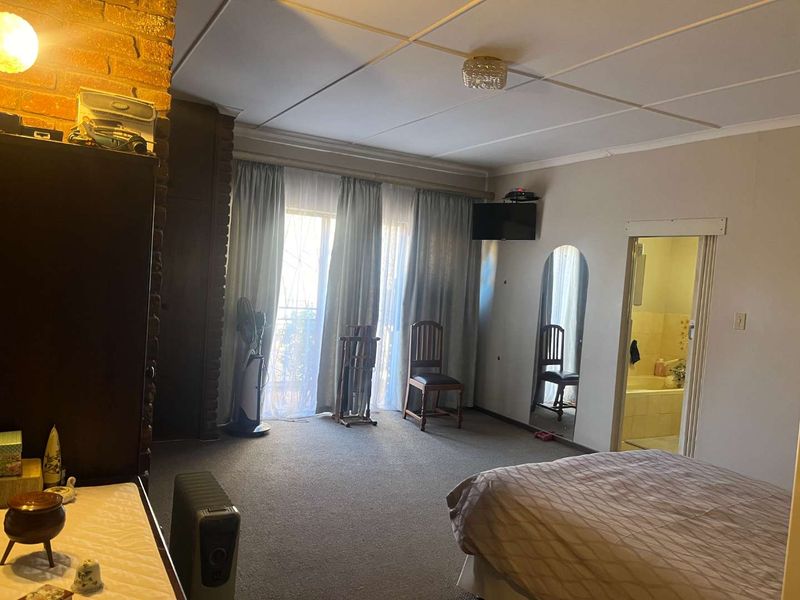 Spacious bedroom featuring an exposed brick pillar, carpeted flooring, and direct access to an en-suite bathroom through a standard doorway.
