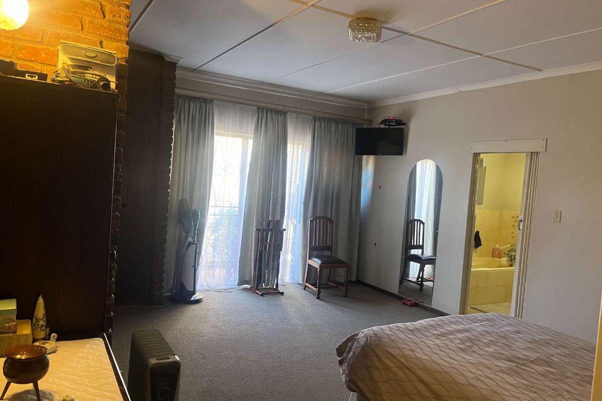 Spacious bedroom featuring an exposed brick pillar, carpeted flooring, and direct access to an en-suite bathroom through a standard doorway.