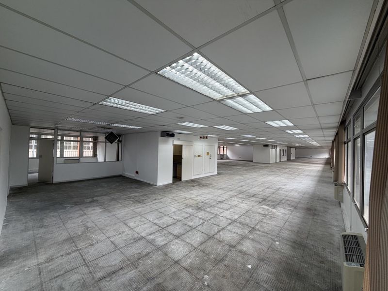 A large, vacant open-plan industrial office space featuring suspended ceilings, recessed lighting, and carpeted flooring, offering a blank canvas for custom fit-outs.