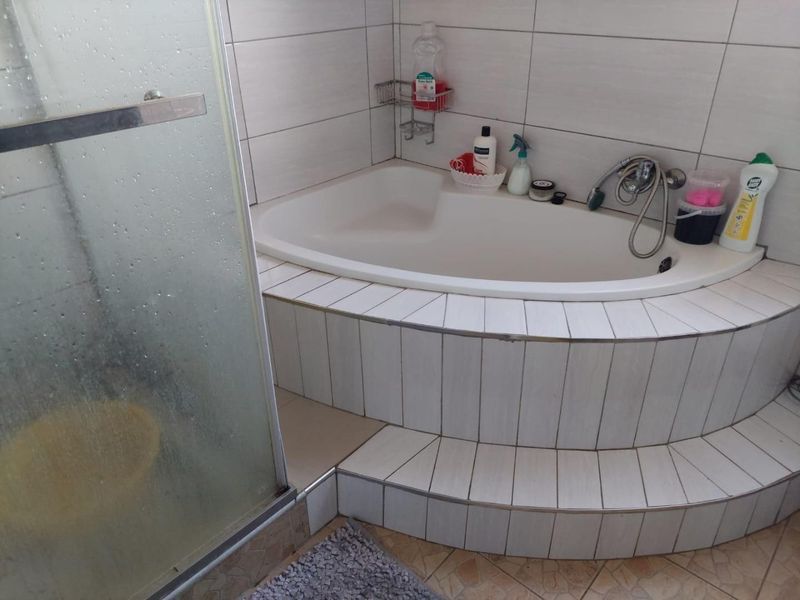 A bathroom featuring a built-in corner bathtub with tiled surround and a separate shower enclosure with glass door.