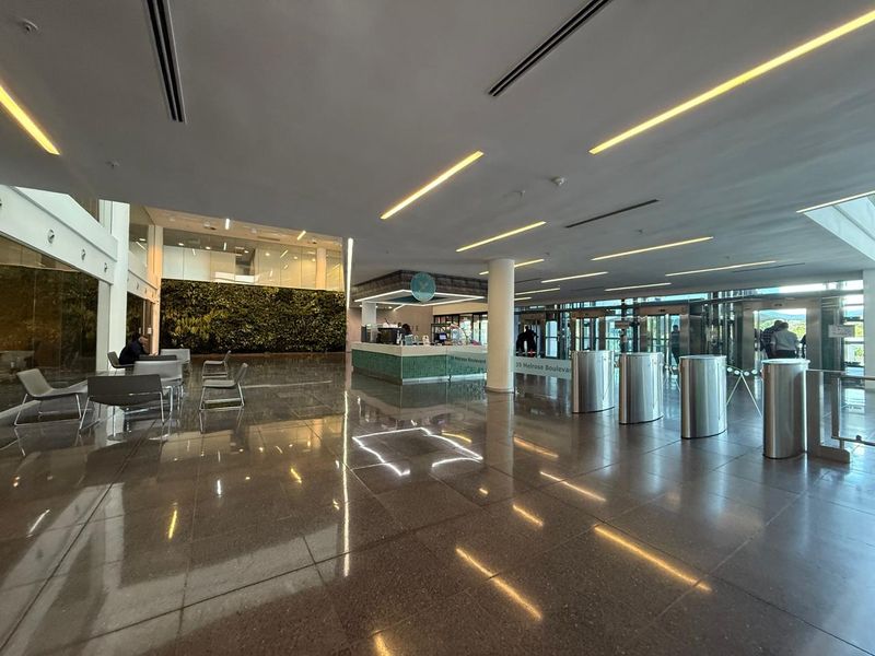 Modern office building lobby featuring a reception desk, secure turnstile access, polished stone floors, and a prominent vertical garden wall.
