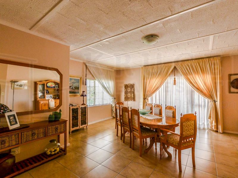Spacious dining room featuring tiled flooring, a textured ceiling, and large sliding glass doors providing access to the exterior.