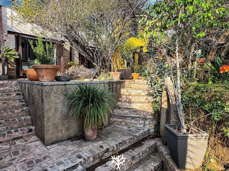 A multi-level rear garden area featuring rustic brick stairs, paved landings, and a retaining wall, providing access to the home via bi-fold doors.