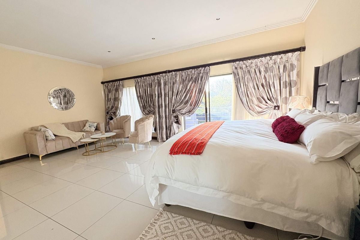 Spacious bedroom featuring large format floor tiles, recessed lighting, and expansive sliding glass doors leading to an outdoor area.