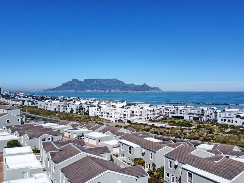 Aerial view of a residential townhouse complex with Table Mountain and ocean views in the background.