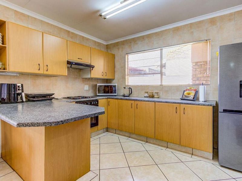 A functional kitchen featuring light wood cabinetry, granite countertops, tiled backsplash, and built-in cooking appliances with tiled flooring.