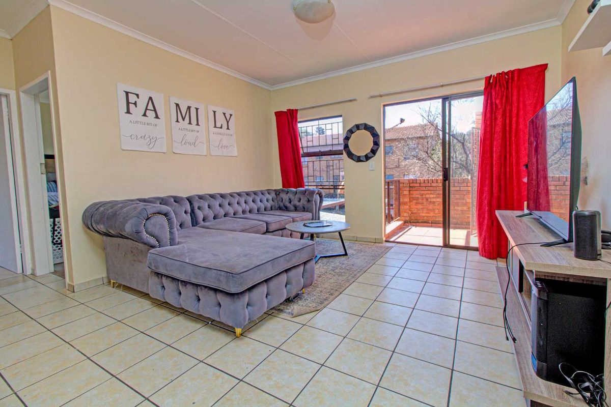 A living room featuring tiled flooring and a sliding glass door that opens onto a private balcony.