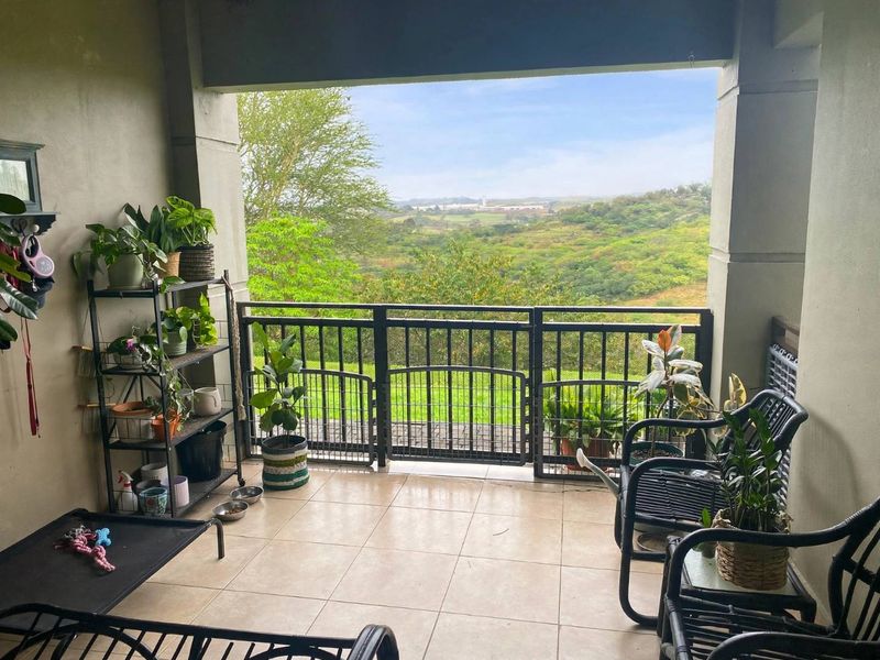 A covered balcony featuring tiled flooring and a metal balustrade, offering scenic views of the surrounding landscape.