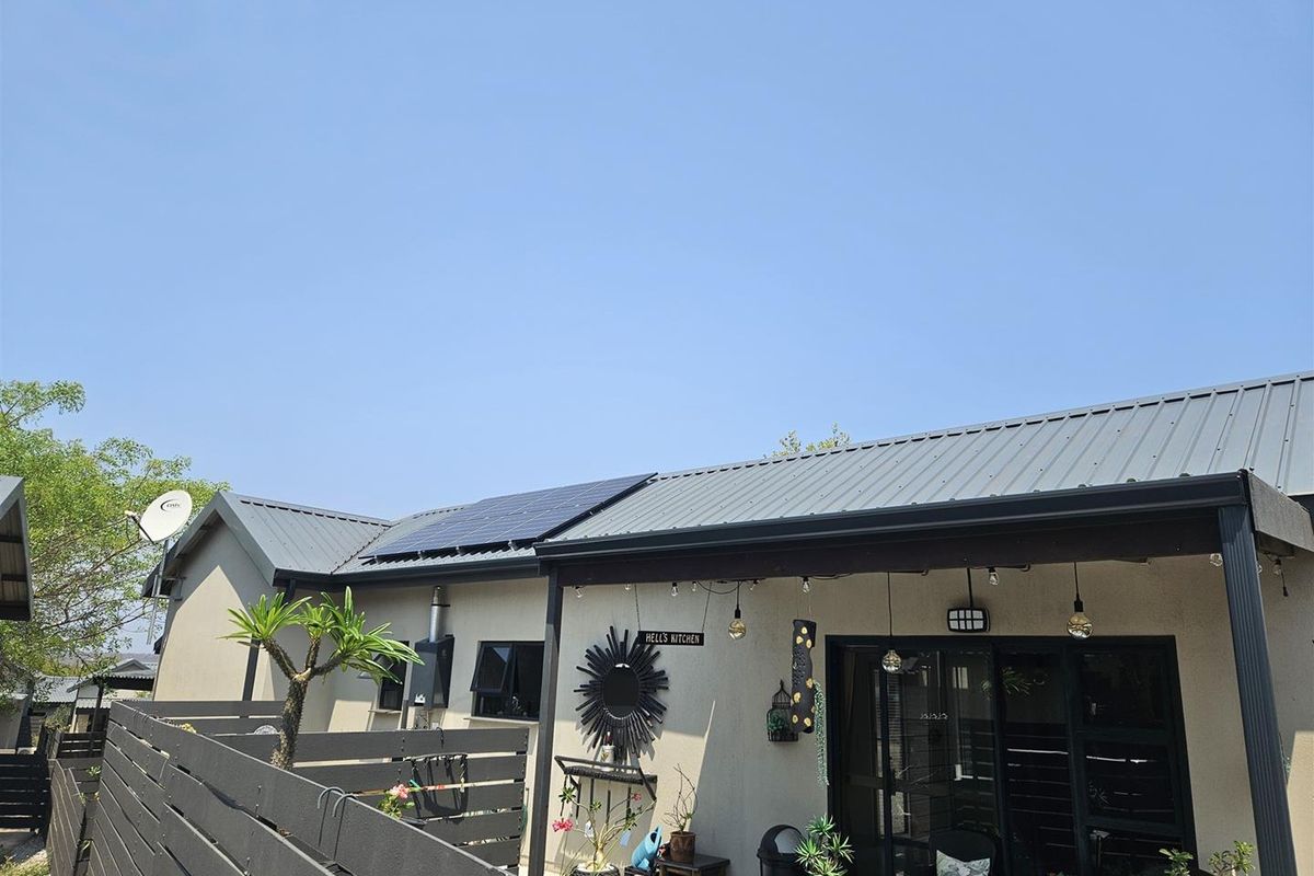 Rear exterior view of the house featuring a covered patio, metal roofing, and installed solar panels.