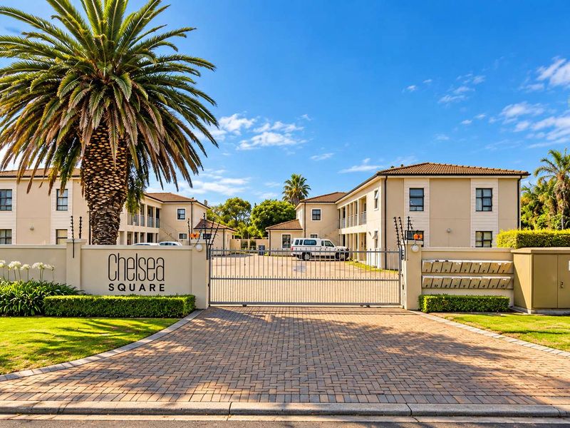 Front entrance view of Chelsea Square apartment complex featuring a secure gated access, paved driveway, and well-maintained landscaped grounds.