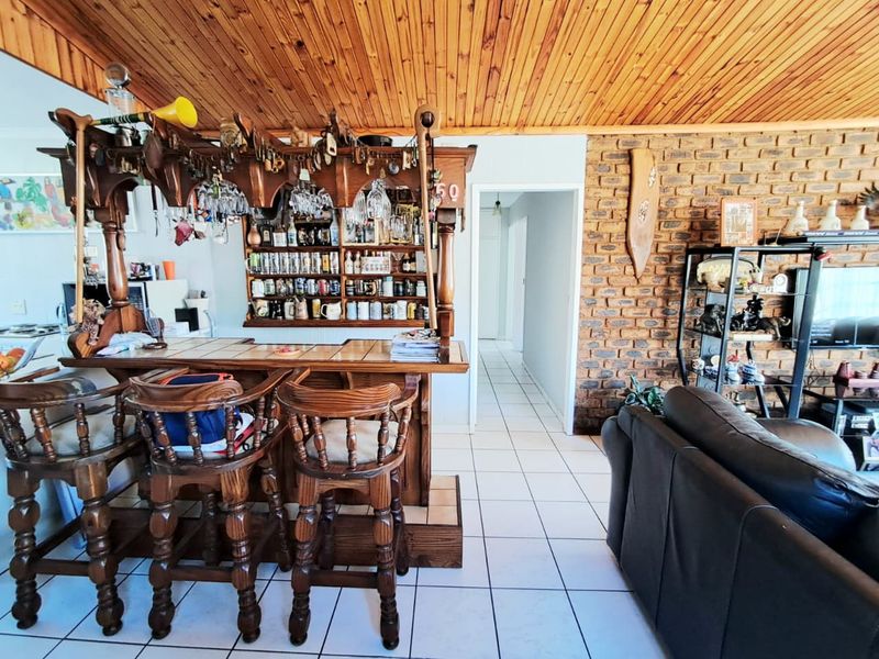 A dedicated bar area featuring a built-in wooden counter, exposed brick feature wall, and timber ceiling, providing a rustic entertainment space.