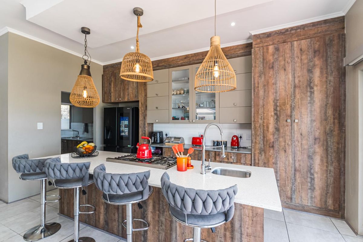 Modern kitchen featuring a central island with a built-in gas hob, stone countertops, and integrated cabinetry with a warm wood-grain finish.