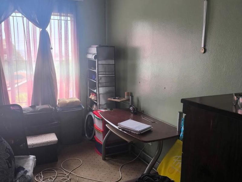 A bedroom featuring carpeted flooring, coved ceilings, and security bars on the window, currently used as a home office space.