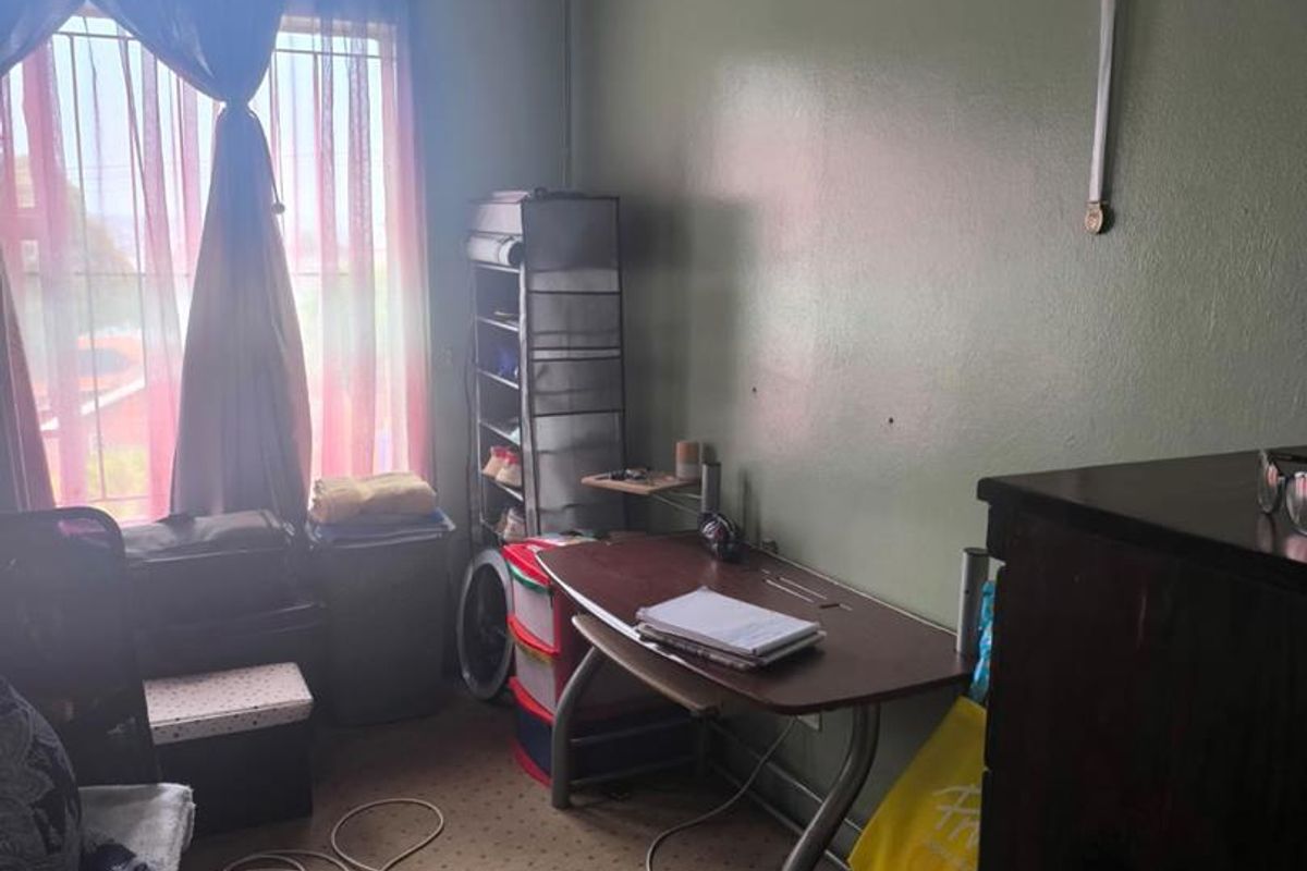 A bedroom featuring carpeted flooring, coved ceilings, and security bars on the window, currently used as a home office space.