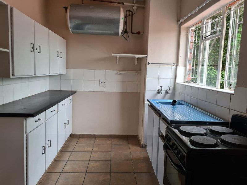 A functional kitchen featuring built-in cabinetry, a tiled backsplash, and an electric stove. The space is ready for modernization and cosmetic updates.