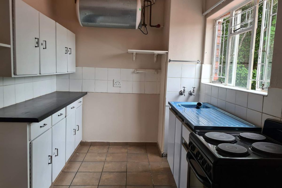 A functional kitchen featuring built-in cabinetry, a tiled backsplash, and an electric stove. The space is ready for modernization and cosmetic updates.