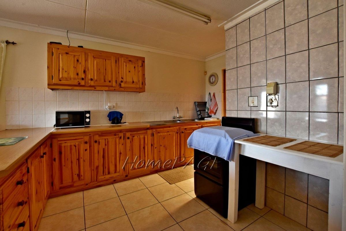A dated kitchen featuring wooden cabinetry, tiled flooring, and tiled splashbacks, offering a functional layout with built-in counter space.