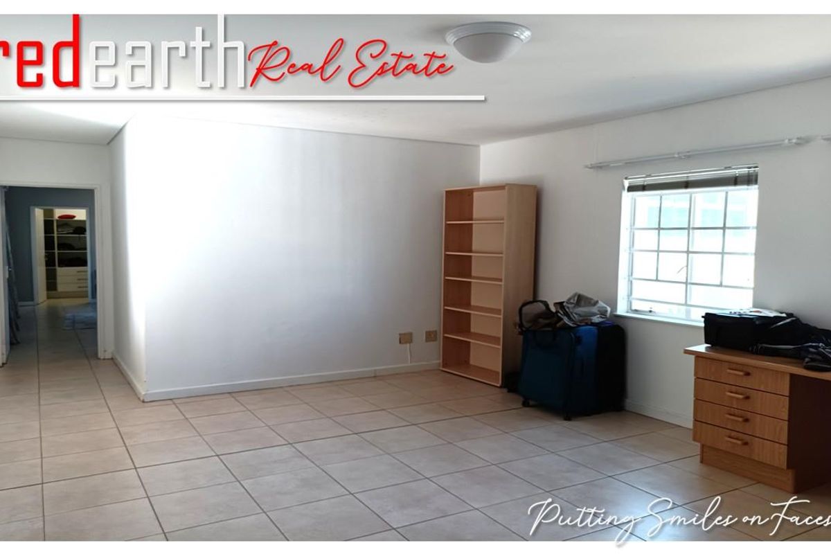 A spacious bedroom featuring tiled flooring, a window with blinds, and a neutral color palette, offering a clean and functional living space.