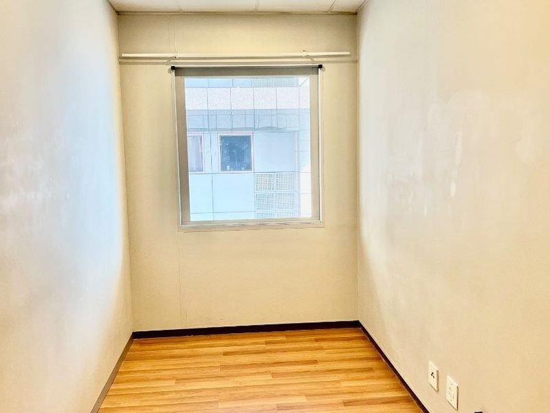 An empty bedroom featuring laminate flooring, a drop ceiling, and a window, providing a blank canvas for potential interior design and staging.