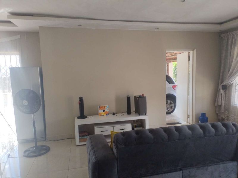 A living room featuring tiled flooring and a recessed ceiling detail, with direct access to an exterior area.