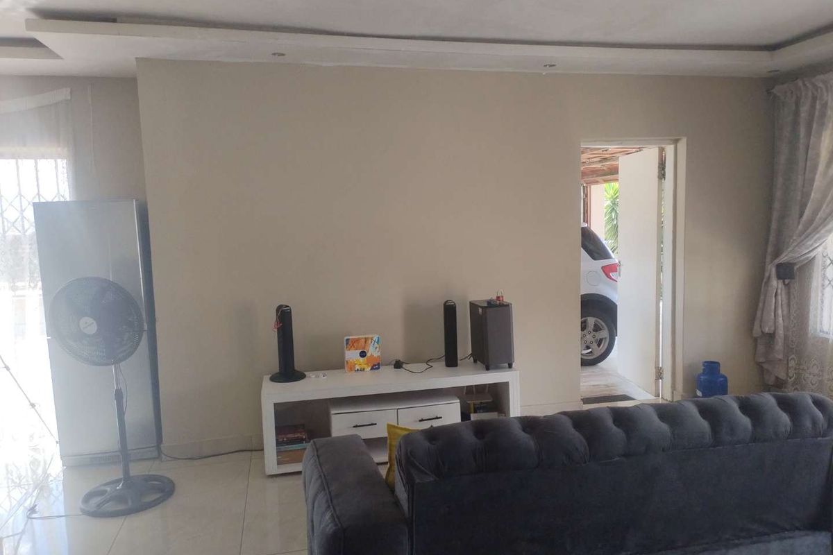 A living room featuring tiled flooring and a recessed ceiling detail, with direct access to an exterior area.
