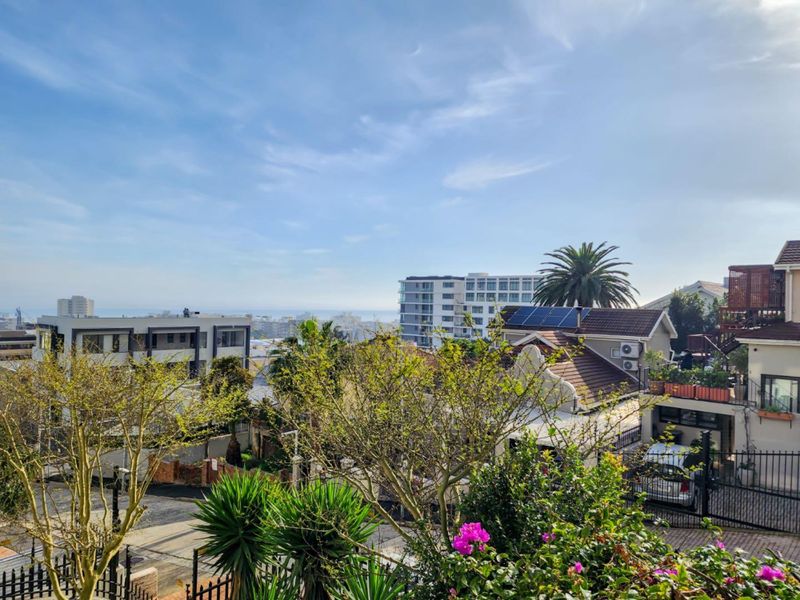 An elevated outdoor view overlooking a residential neighbourhood with distant ocean glimpses and clear blue skies.