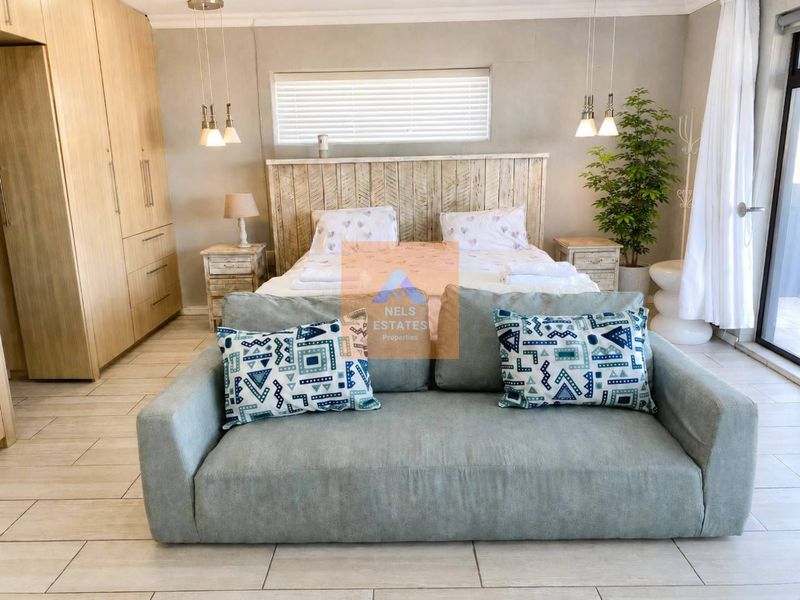 A well-lit bedroom featuring built-in cupboards, tiled flooring, and modern pendant lighting, offering a comfortable and functional living space.