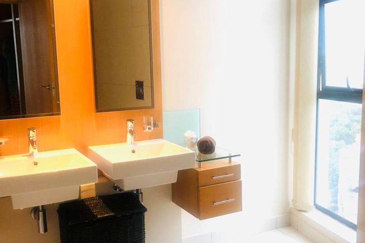 Modern bathroom featuring dual wall-mounted vanity basins, sleek cabinetry, large mirrors, and floor-to-ceiling windows providing ample natural light.