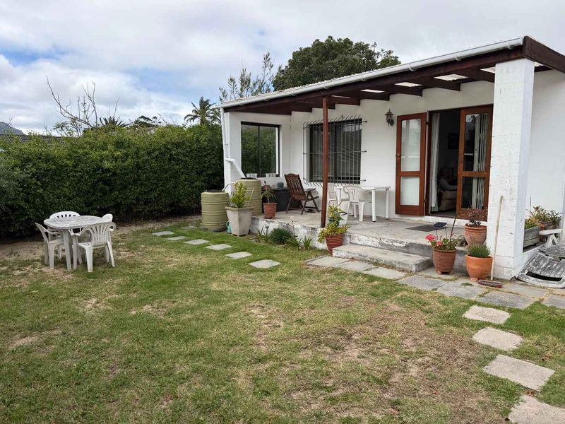 Rear view of the apartment featuring a covered patio with timber pergola, sliding glass doors, and a private garden area.