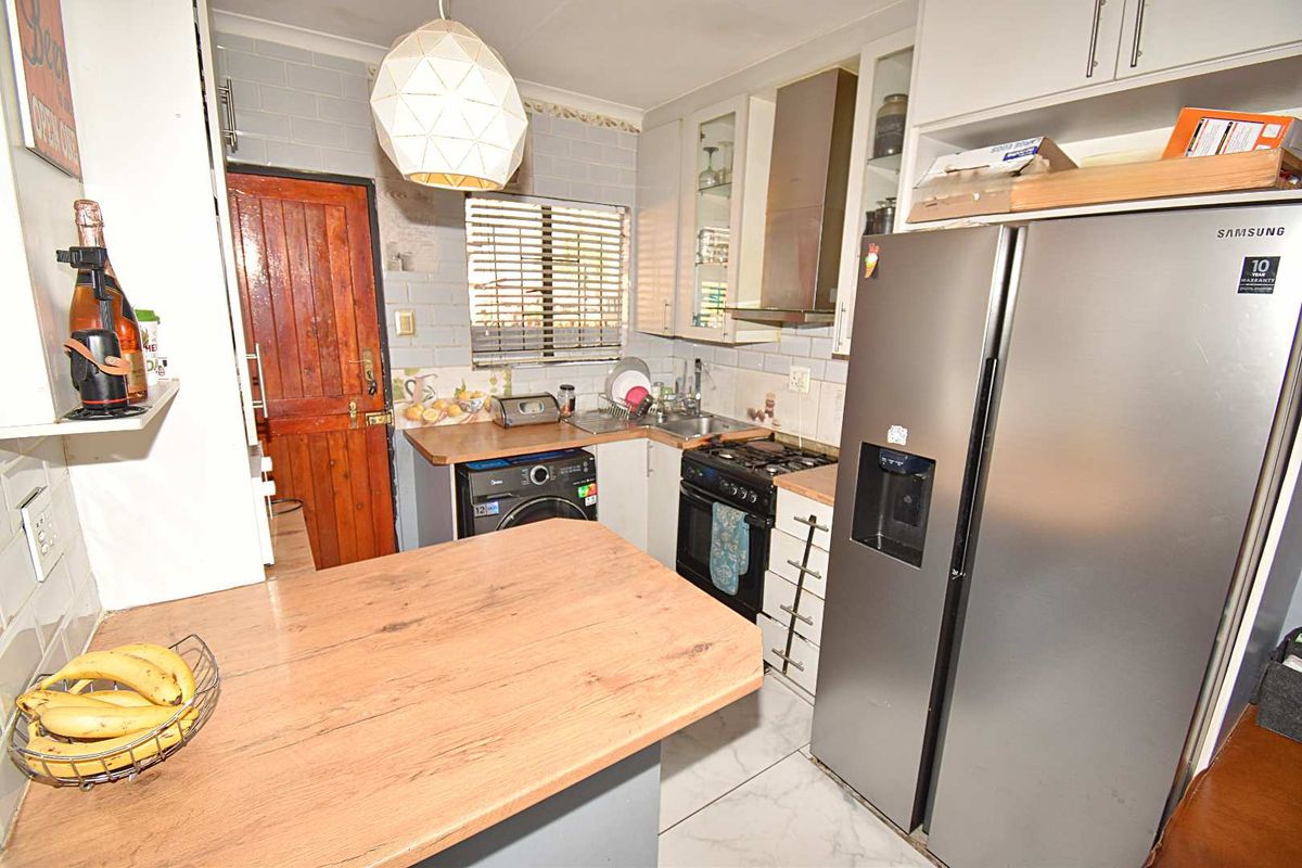 Compact kitchen featuring built-in cabinetry, laminate countertops, gas stove with extractor fan, and tiled backsplash, offering functional preparation space.