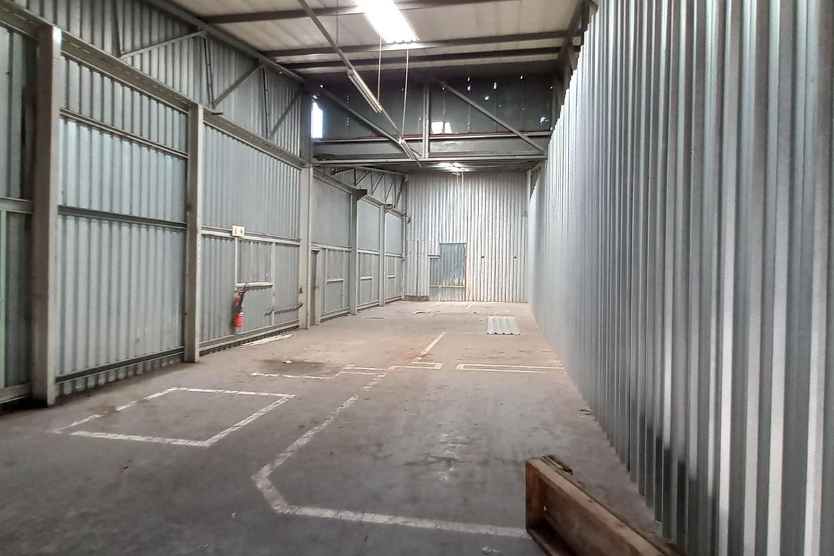 Spacious industrial utility area featuring corrugated metal walls, exposed steel roof structure, and durable concrete flooring, suitable for storage or workshop use.