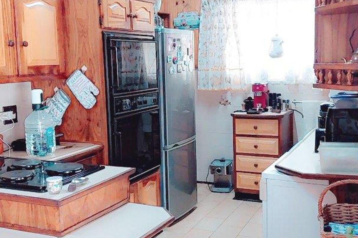 A dated kitchen featuring extensive timber paneling, built-in wooden cabinetry, a built-in oven, and tiled flooring.
