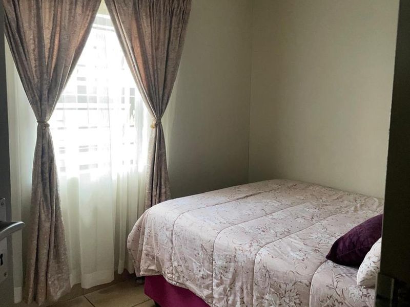 A compact bedroom featuring tiled flooring and natural light through a window with installed curtain rails.