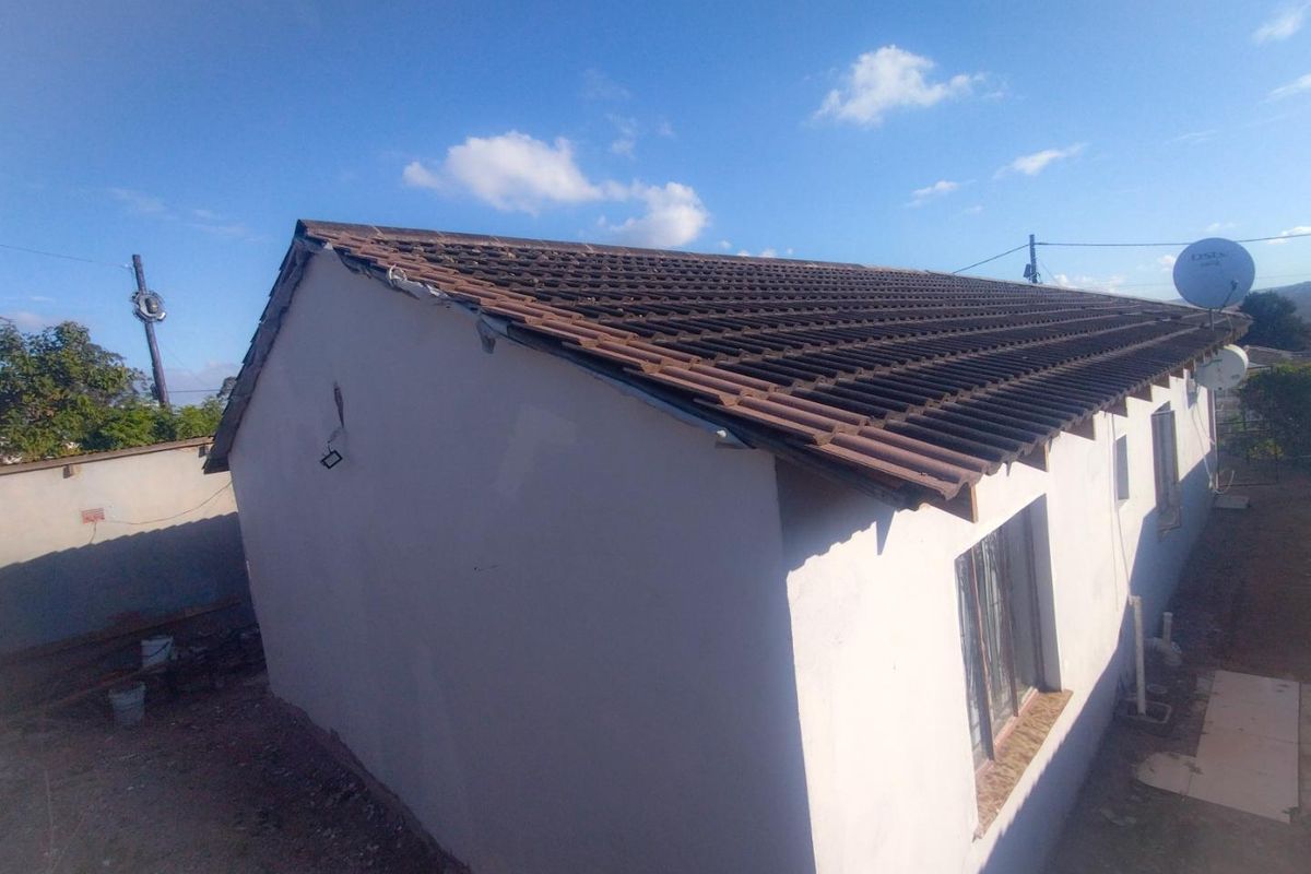 Rear exterior view of the house showing the tiled roof structure and exterior walls with visible maintenance requirements.