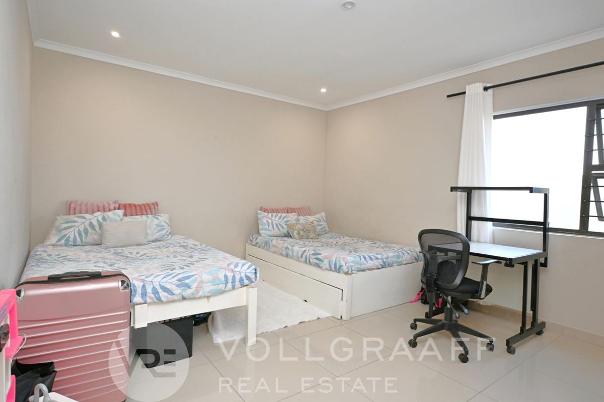 A well-lit bedroom featuring neutral wall tones, tiled flooring, and large windows, providing a comfortable and functional living space.