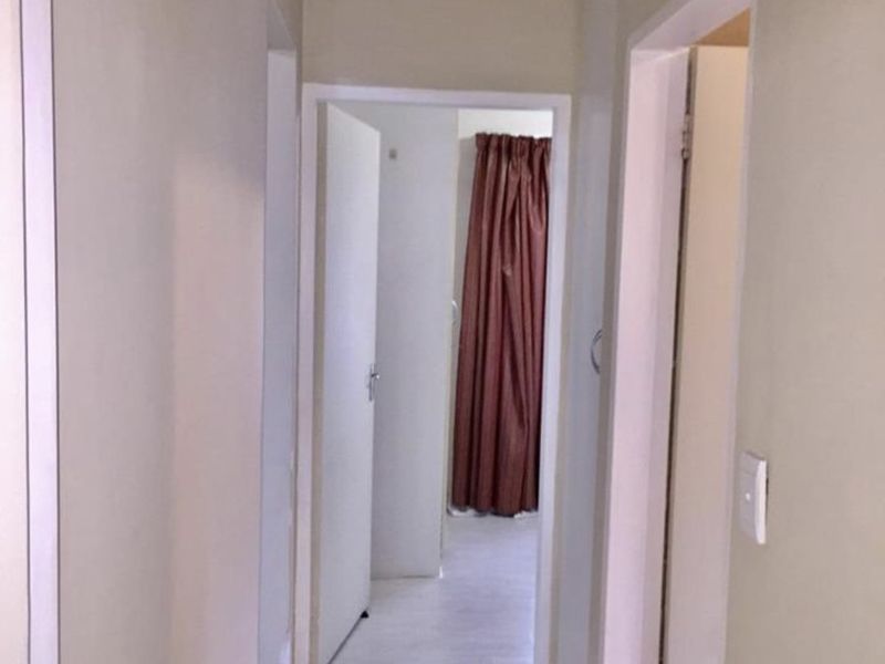 A functional hallway featuring tiled flooring and built-in storage cupboards, providing access to adjacent rooms within the apartment.