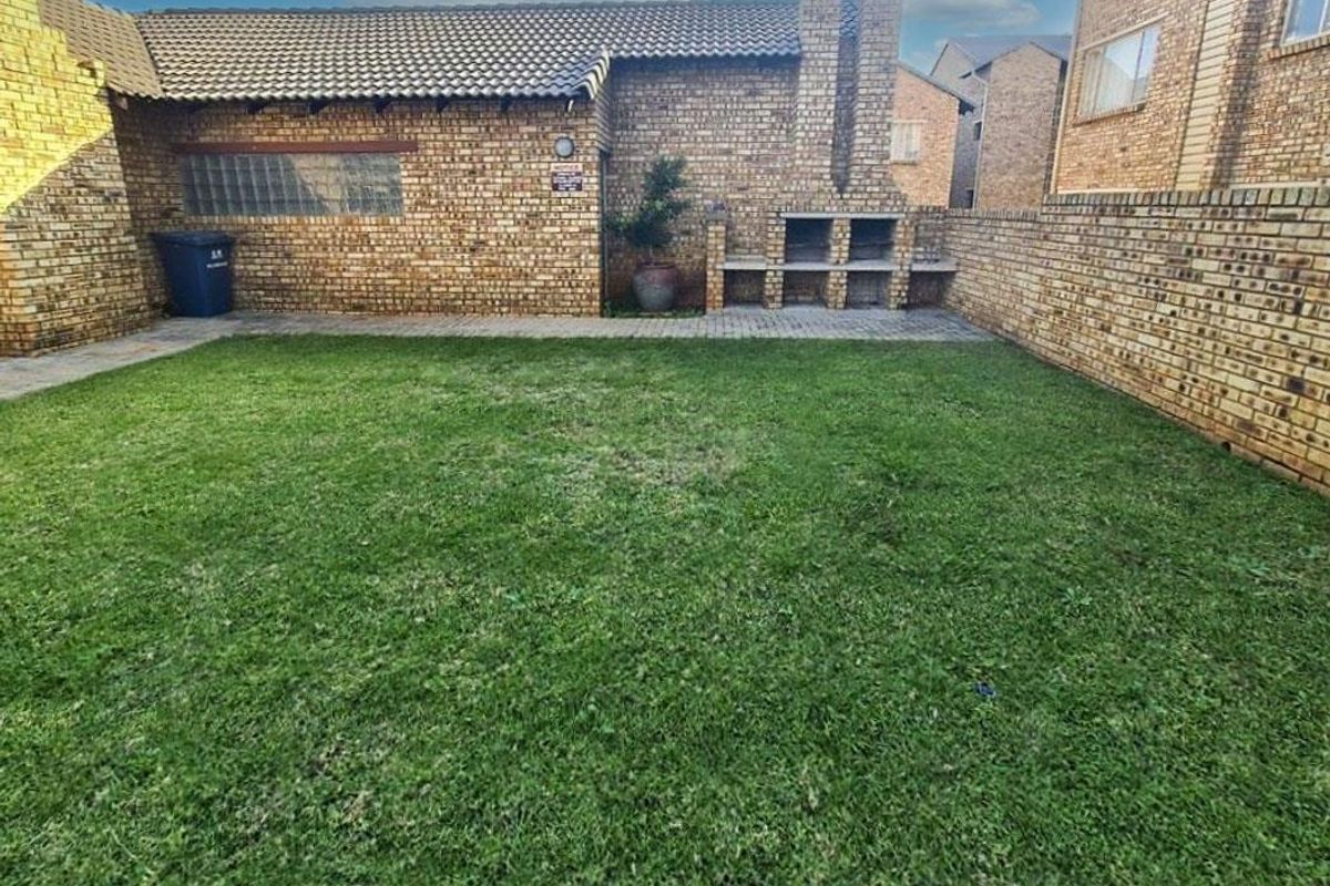 Private rear garden featuring a lawn area, brick boundary walls, and a built-in outdoor braai facility.