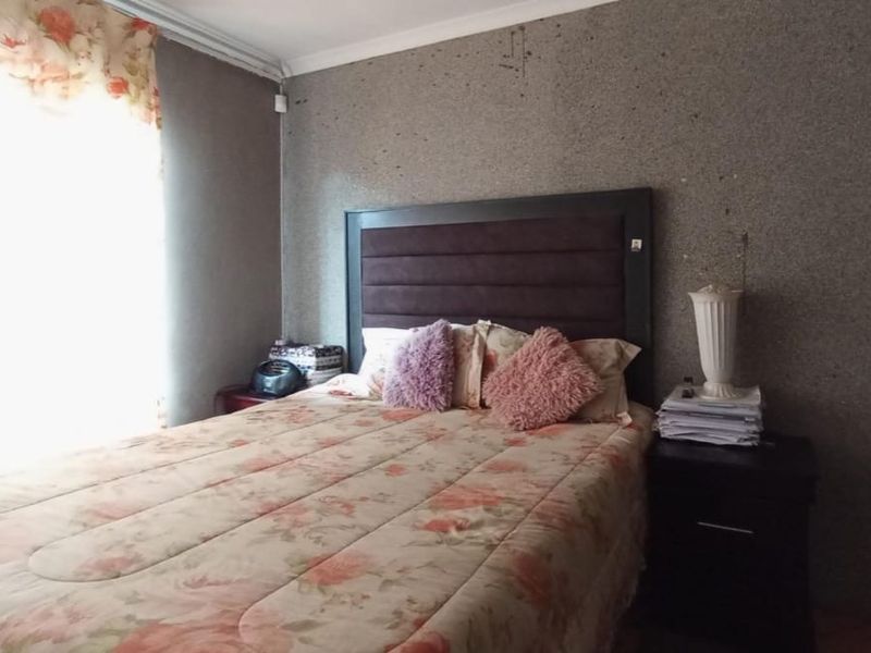 A bedroom featuring textured wall finishes and coving, currently showing signs of wear and surface damage on the main wall.