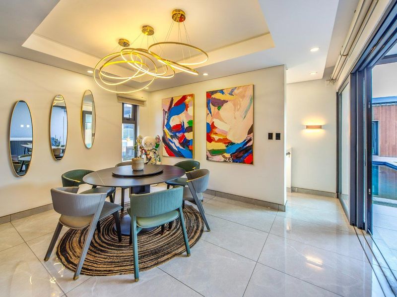 Elegant dining area featuring polished porcelain flooring, a recessed ceiling with contemporary pendant lighting, and large sliding glass doors opening to the pool area.