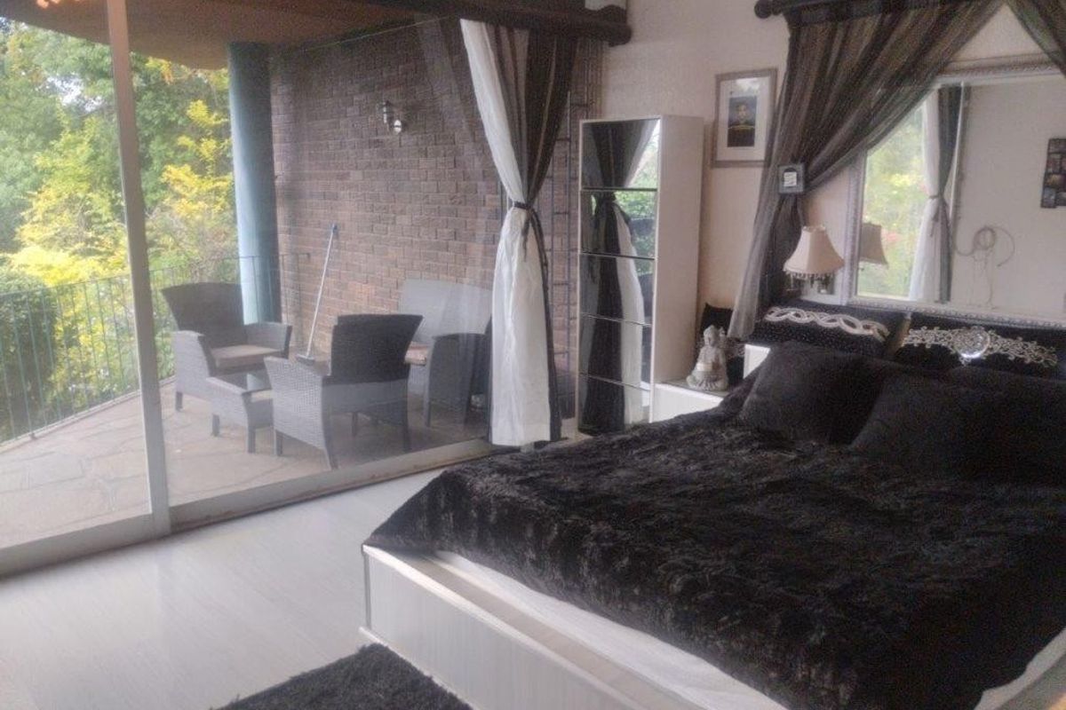 Spacious bedroom featuring large sliding glass doors that open onto a private balcony with an exposed brick wall.