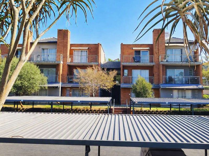 Front view of a multi-story brick townhouse complex featuring private balconies and covered parking bays.