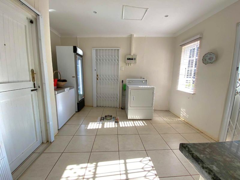 A functional laundry room featuring tiled flooring, recessed lighting, and a security gate, providing a practical utility space for the home.