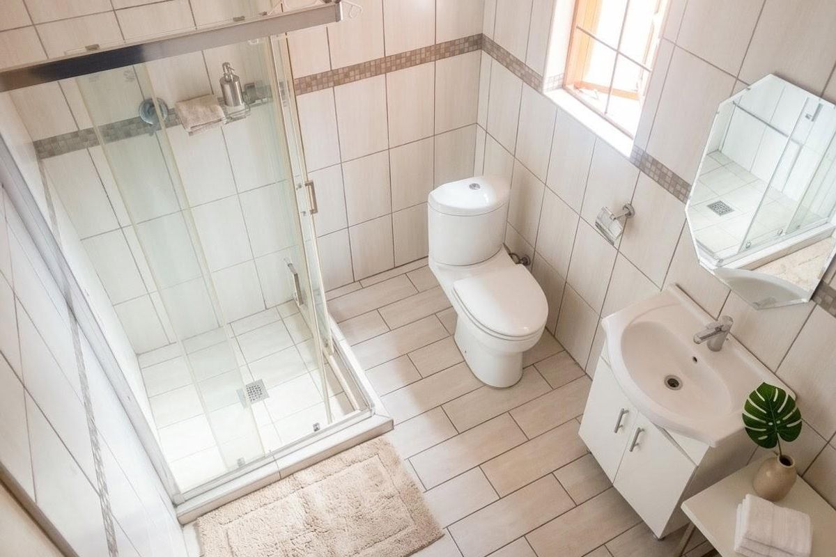 A clean, well-maintained bathroom featuring a glass shower enclosure, a modern toilet, and a vanity unit with a basin.