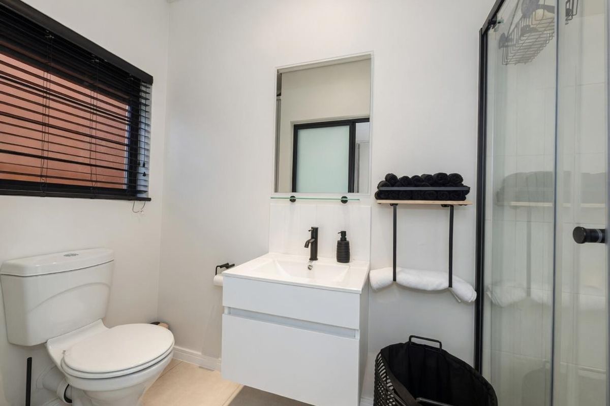 A modern, well-maintained bathroom featuring a floating vanity, a glass-enclosed shower, and a contemporary toilet.