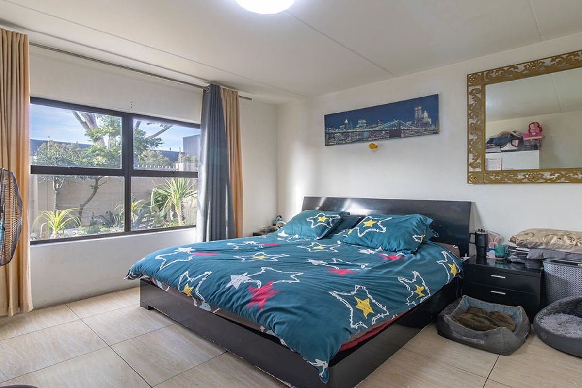 A well-lit bedroom featuring large windows with curtain tracks and neutral tiled flooring, offering a comfortable and functional living space.