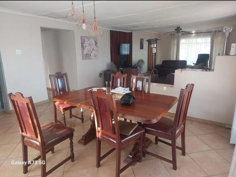 Open-plan dining and living area featuring tiled flooring, pendant lighting, and a half-height partition wall separating the spaces.