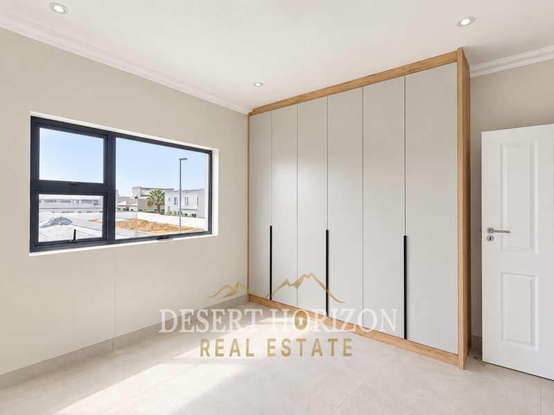 A bright, modern bedroom featuring neutral tiled flooring, recessed downlights, and extensive floor-to-ceiling built-in cupboards with a contemporary finish.