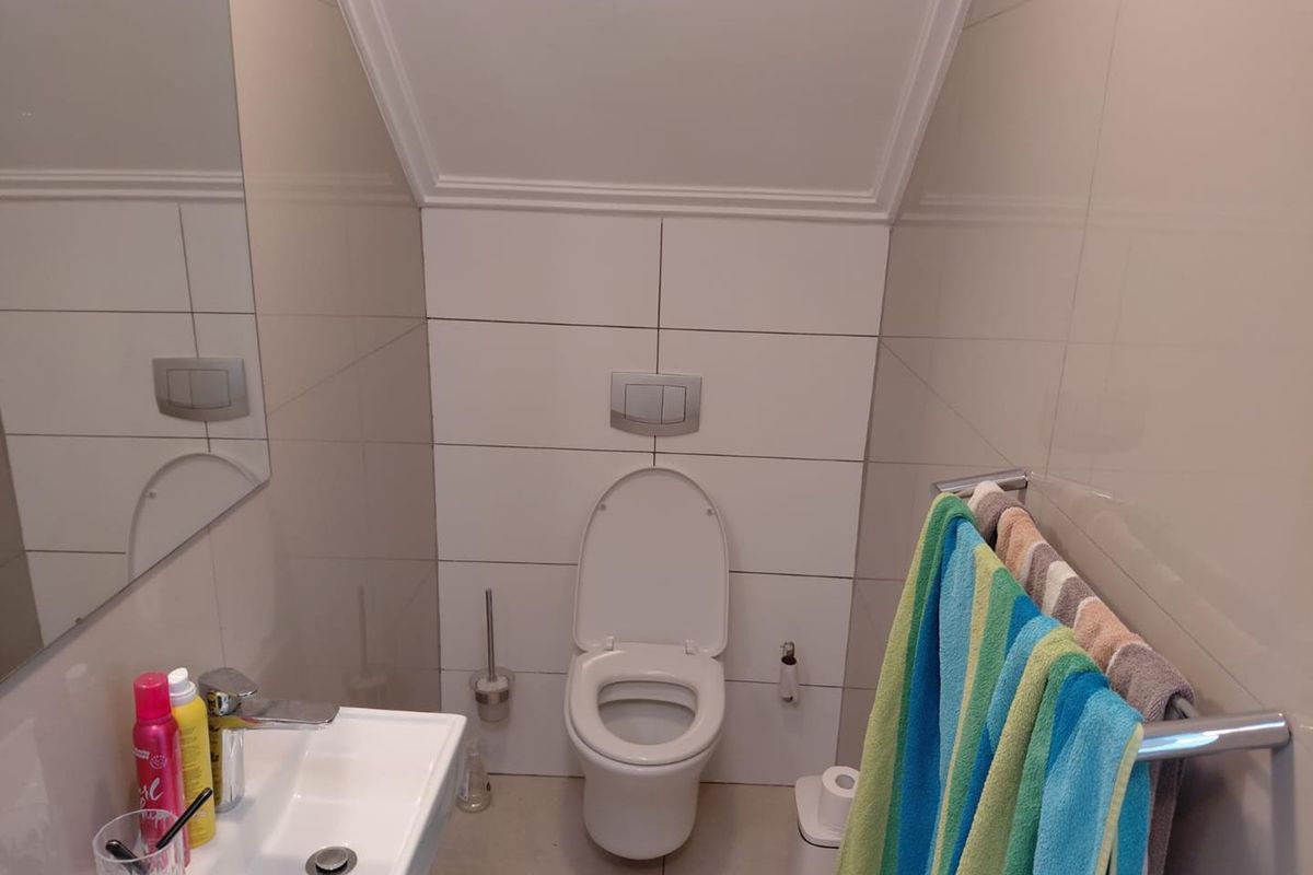 A compact, modern bathroom featuring a wall-mounted toilet with a concealed cistern, a sleek basin with a chrome mixer tap, and neutral wall tiling.