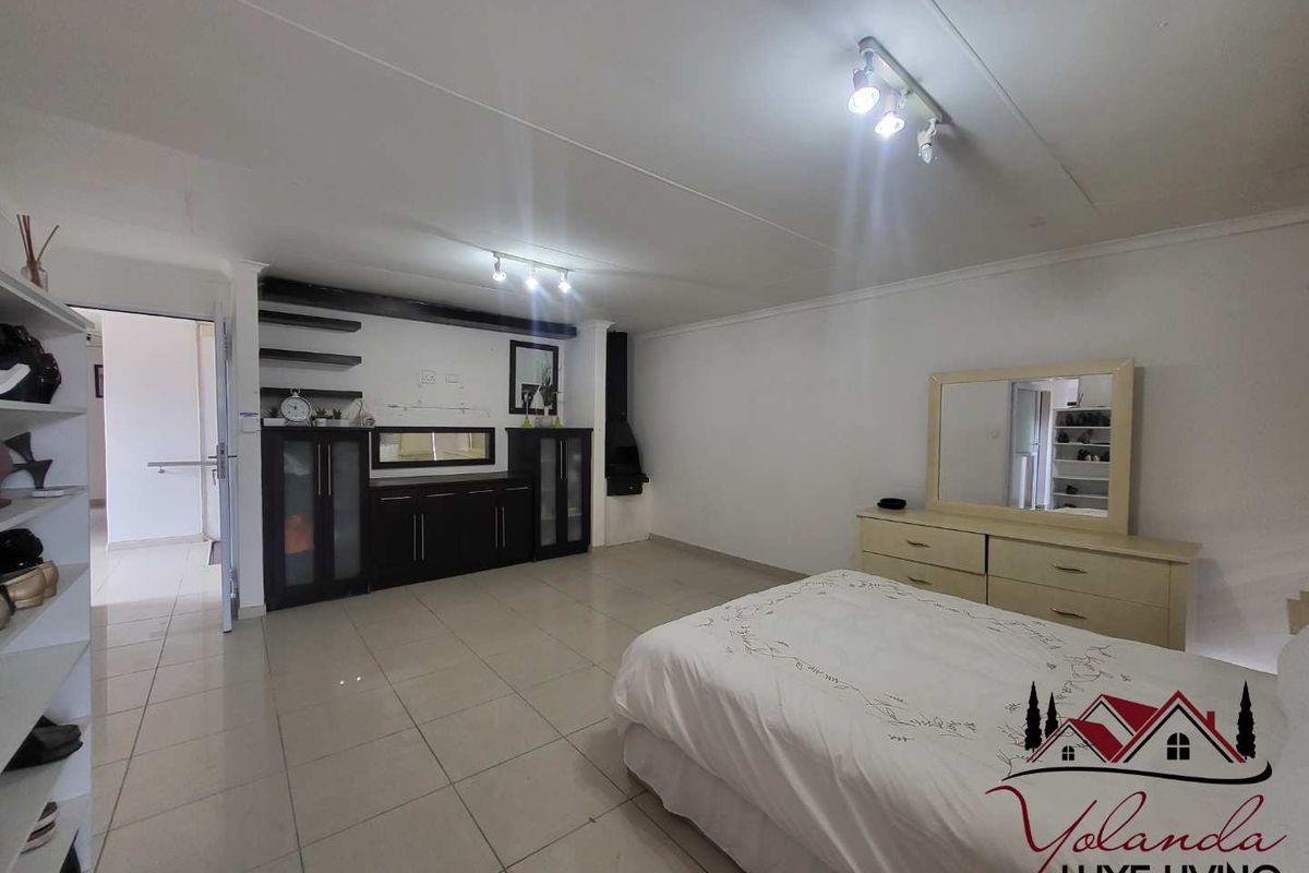 Spacious bedroom featuring tiled flooring, built-in cabinetry, and a fireplace, offering a functional layout with ample storage space.