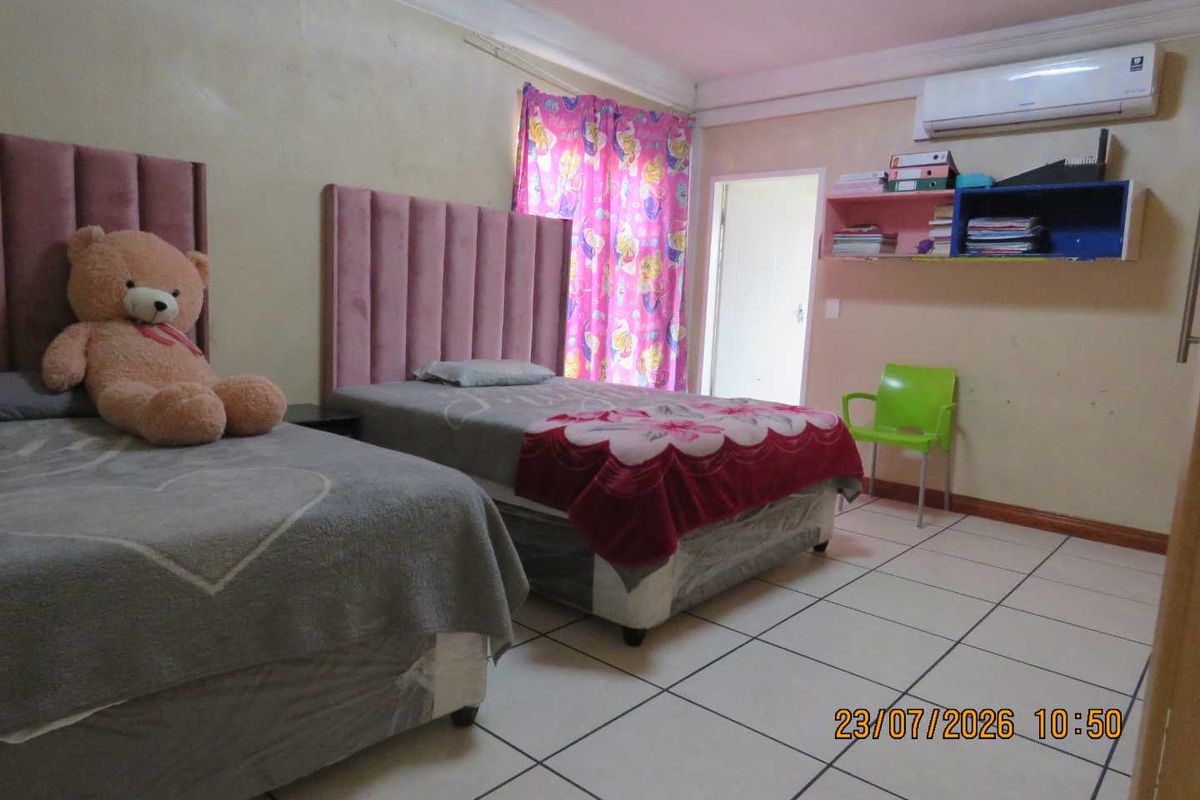 A bedroom featuring tiled flooring, a wall-mounted air conditioning unit, and built-in shelving, requiring minor cosmetic updates to the wall finishes.
